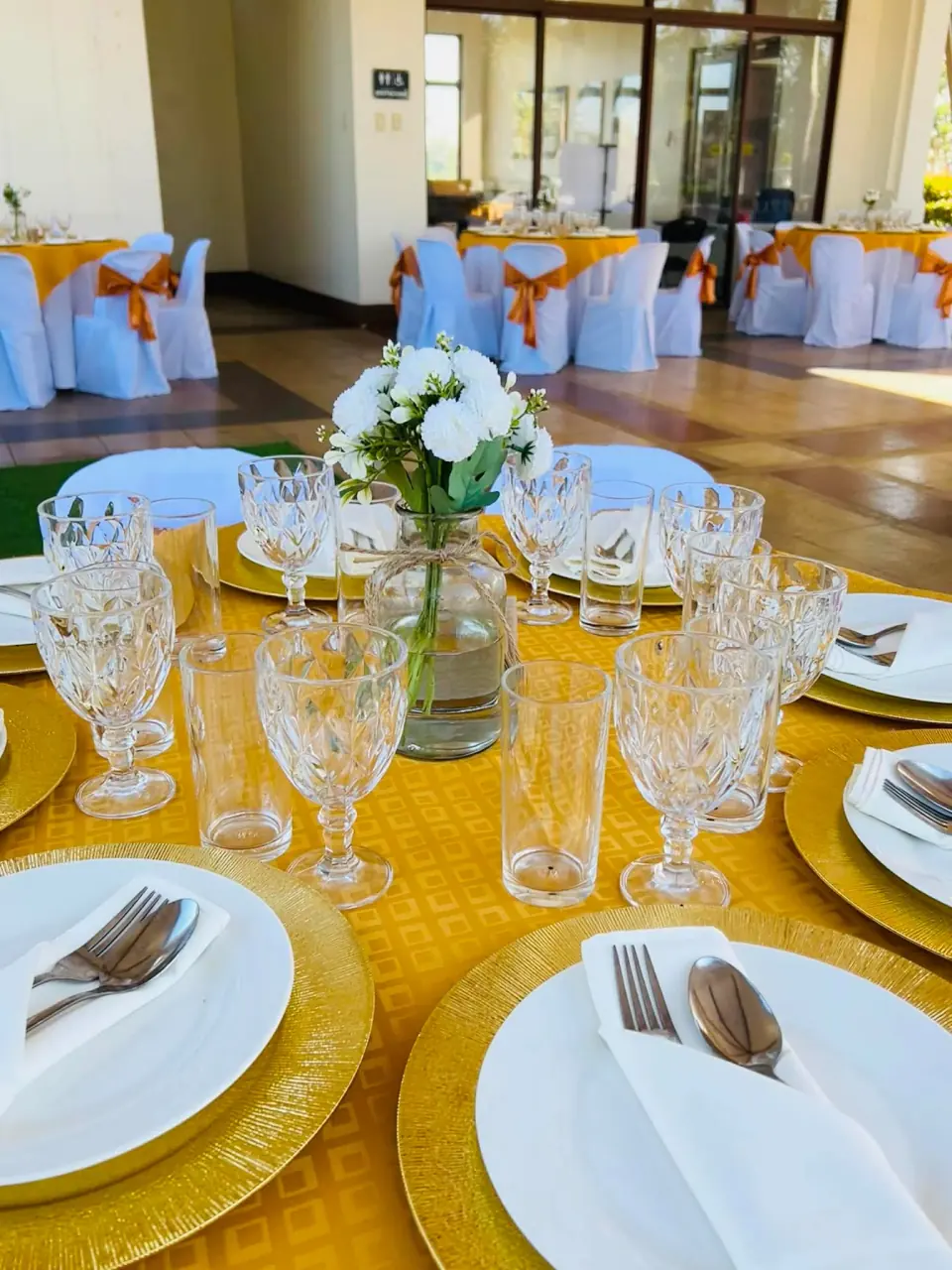 Blue and gold event table setting with glassware and floral centerpiece