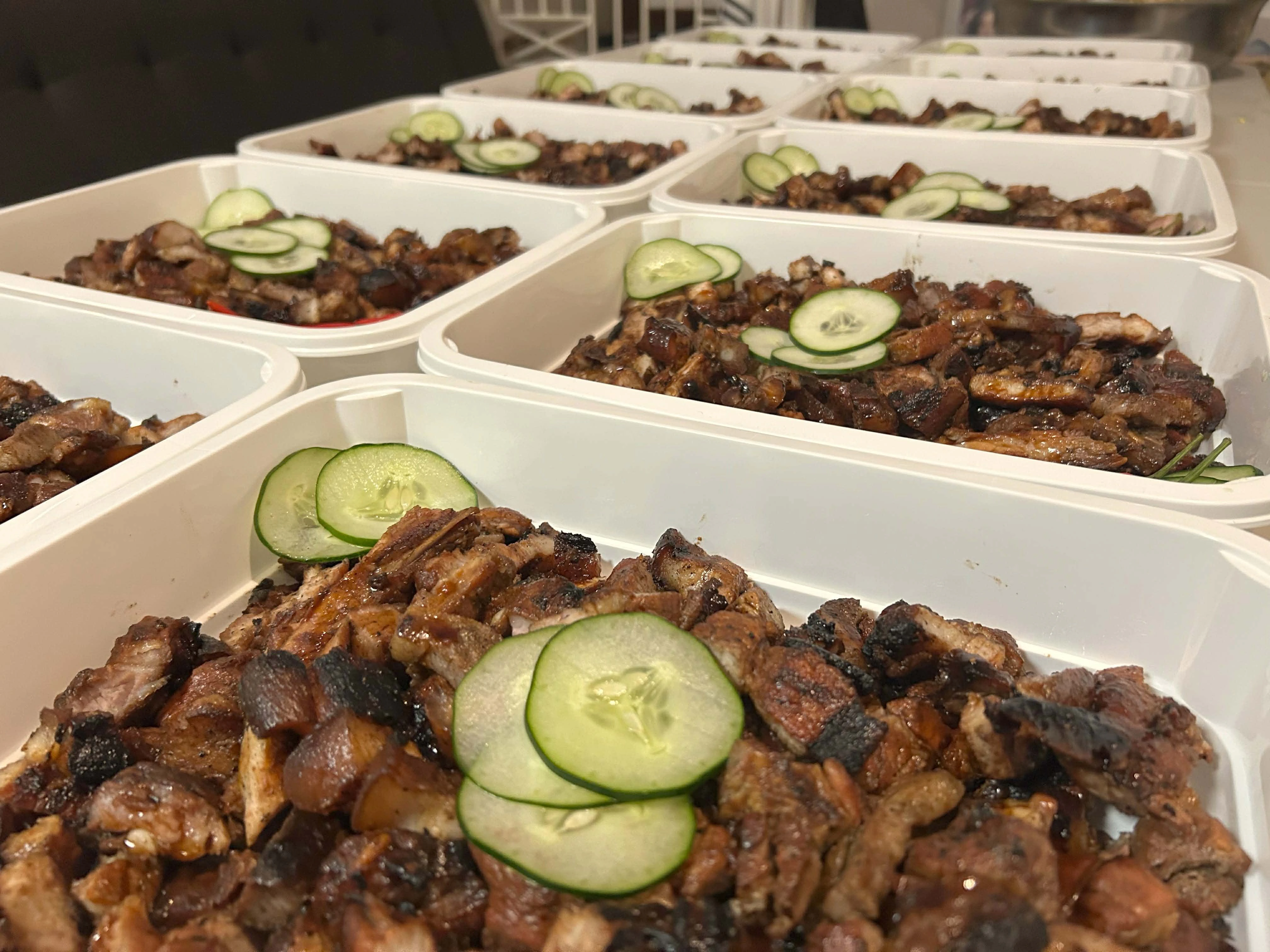 Rows of grilled meat packed meals prepared for a group